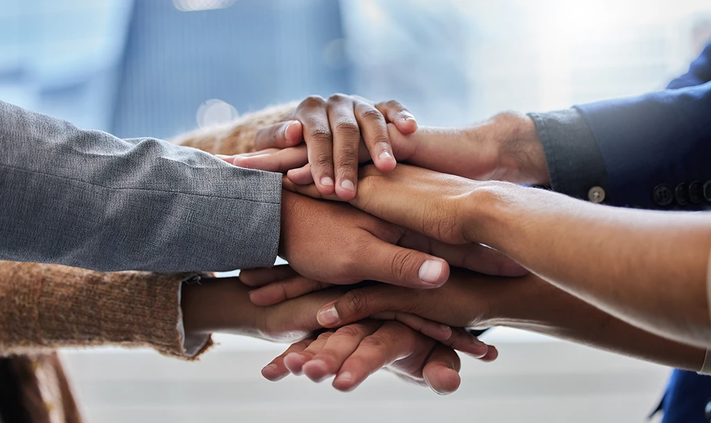 People, hands and huddle in office for teamwork, collaboration and partnership together